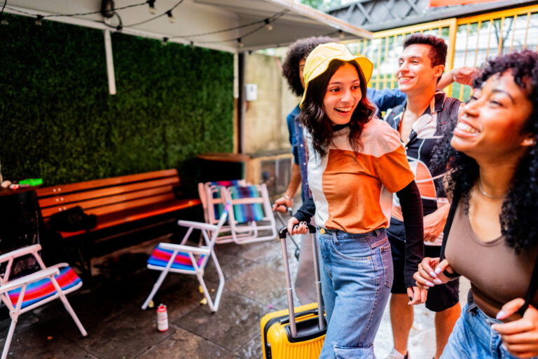 Gen Z travellers walking together with their luggage and smiling